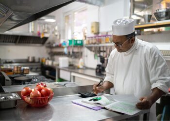Professional chef calculating food cost in commercial restaurant kitchen