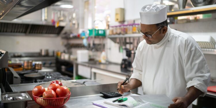 Professional chef calculating food cost in commercial restaurant kitchen