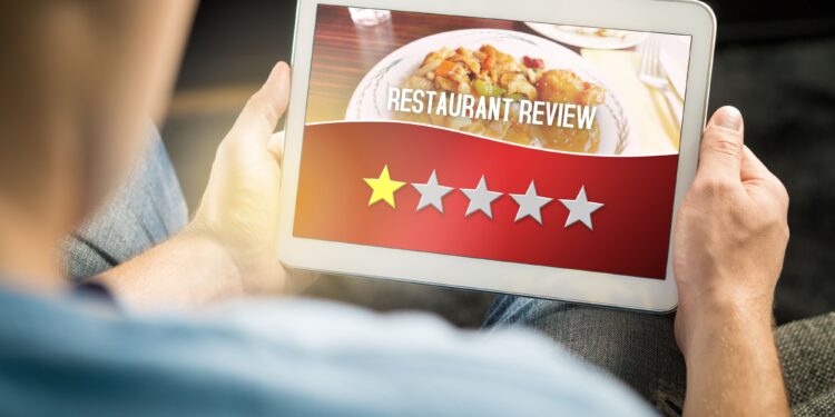 Restaurant professional using tablet to collect customer feedback and prevent negative reviews