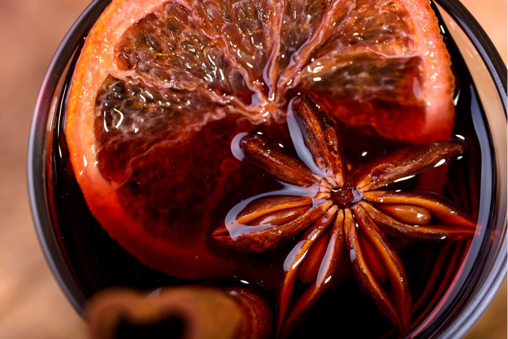 red mulled wine with orange slice and spice in glas for holiday beverage