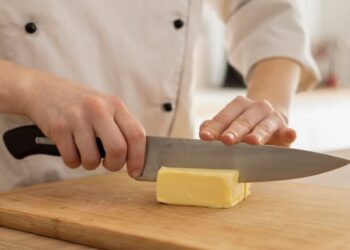 Cook cutting Butter with a chef knife on a board