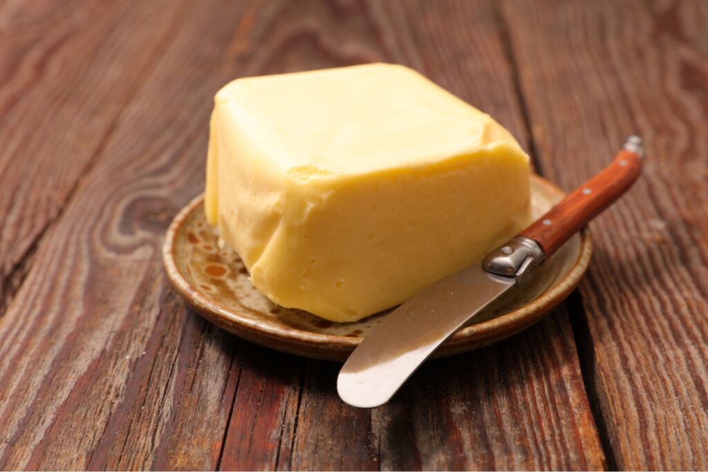 Fresh butter block with butter knife on a plate and wooden table