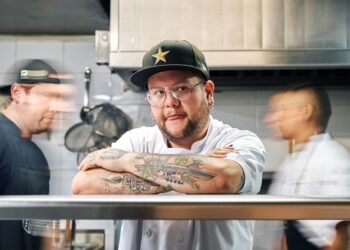 professional chef with tattoos on his arms on the pass in the kitchen