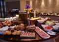 Hotel breakfast buffet display with fresh fruit, pastries, and hot dishes in upscale restaurant setting