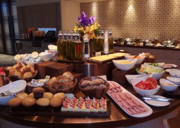 Hotel breakfast buffet display with fresh fruit, pastries, and hot dishes in upscale restaurant setting