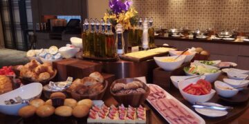 Hotel breakfast buffet display with fresh fruit, pastries, and hot dishes in upscale restaurant setting