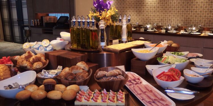 Hotel breakfast buffet display with fresh fruit, pastries, and hot dishes in upscale restaurant setting