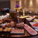 Hotel breakfast buffet display with fresh fruit, pastries, and hot dishes in upscale restaurant setting
