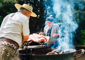 Traditional uruguayan asado meat grilling on parrilla with smoke and flames