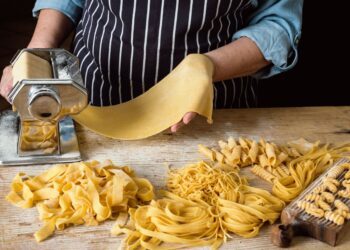Fresh pasta nests dusted with semolina flour drying on a wooden surface before cooking