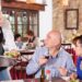 Serveur professionnel servant un plat à une table de restaurant, représentant le respect du serveur dans l'hospitalité