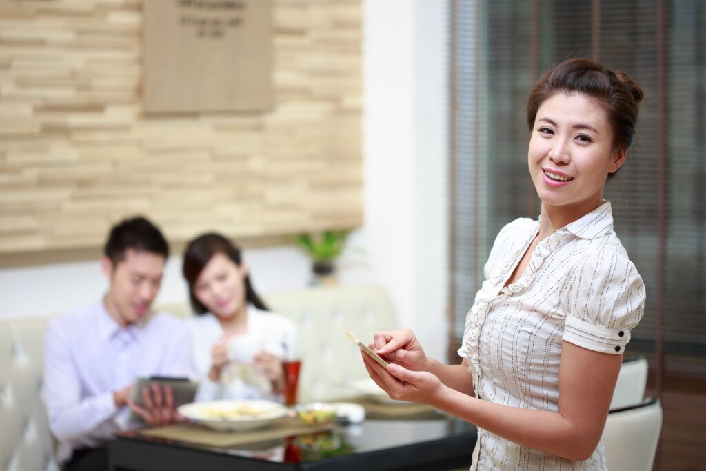 Serveur professionnel servant des clients à une table de restaurant, représentant le respect du serveur dans l'hospitalité