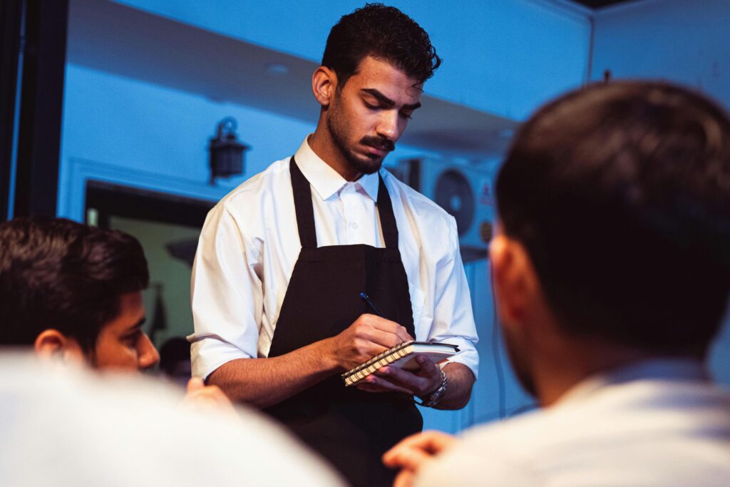 Serveur professionnel apportant le menu au choix aux clients à une table de restaurant, représentant le respect du serveur dans l'hospitalité
