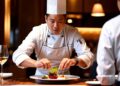 Chef del ristorante che impiatta un piatto estivo utilizzando ingredienti locali freschi di stagione