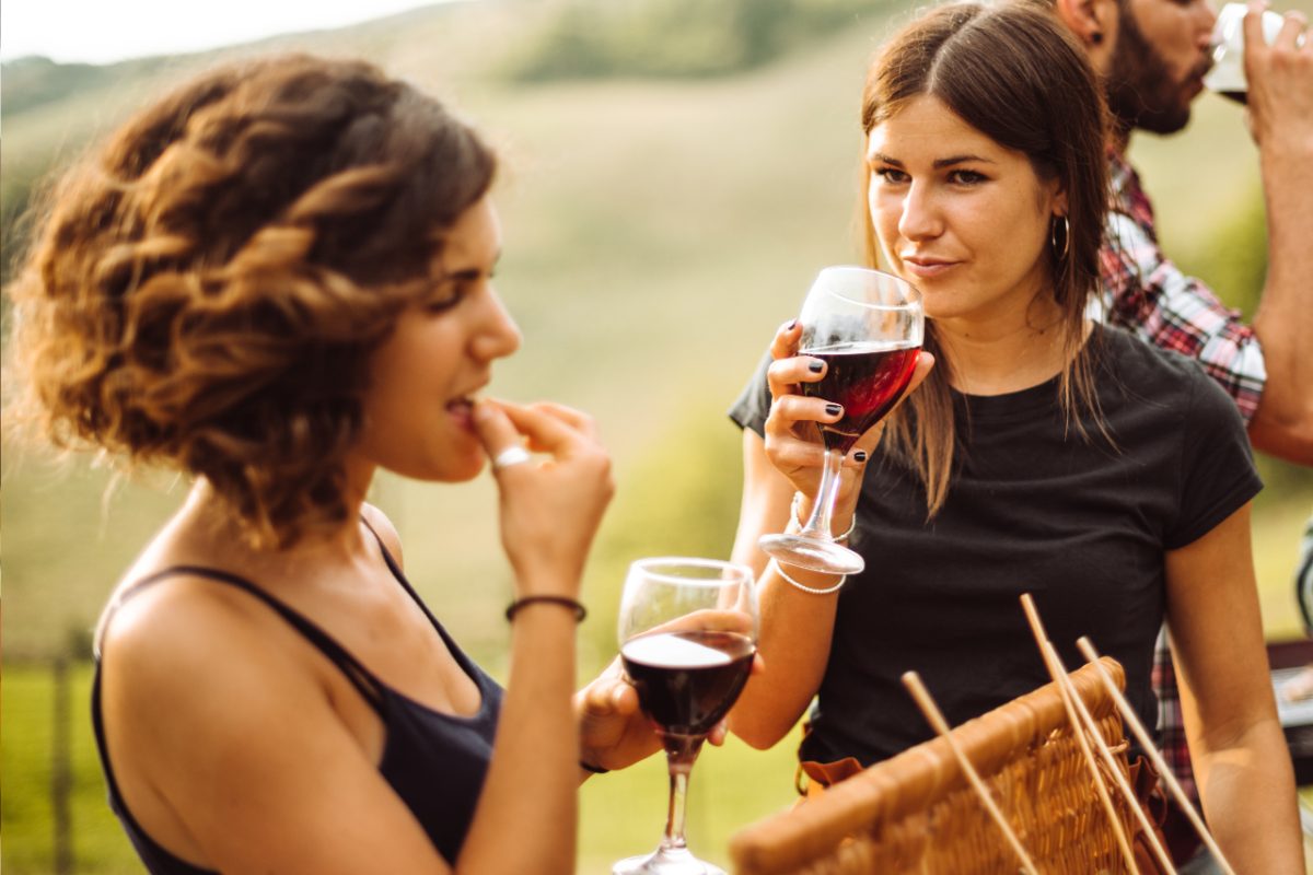 A group of friends laugh and compare drinks at a vendor stall during the Food Festival, exploring global flavors together.