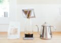 A barista carefully pouring hot water over single-origin coffee grounds in a pour-over dripper at a specialty café
