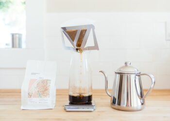 A barista carefully pouring hot water over single-origin coffee grounds in a pour-over dripper at a specialty café