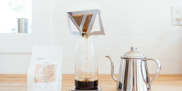 Ein Barista gießt sorgfältig heißes Wasser über Single-Origin-Kaffeepulver in einem Pour-Over-Dripper in einem Spezialitätencafé