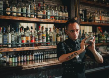 A skilled bartender demonstrating mixology training techniques while preparing a craft cocktail at a restaurant bar