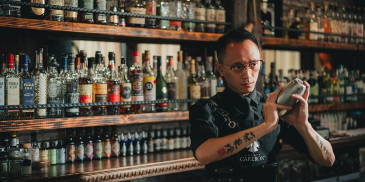 Ein erfahrener Barkeeper, der Mixologie-Techniken anwendet, während er einen handwerklich gefertigten Cocktail an einer Restaurantbar zubereitet