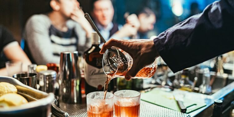 A bartender serves a premium spirit sample at the Food Festival, surrounded by enthusiastic visitors at an outdoor event.