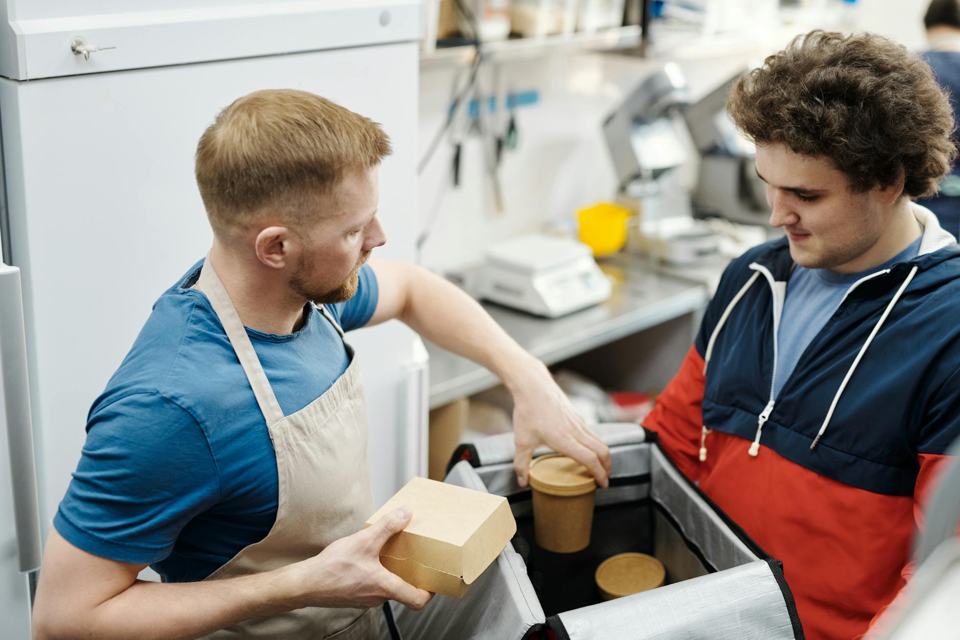 Ein Catering-Teamkollege trägt isolierte Lebensmittelbehälter während des Aufbaus eines Outdoor-Catering-Services an einem Veranstaltungsort.