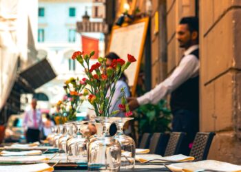 A chef sets a table on a restaurant patio preparing for summer patio service at the start of outdoor season.