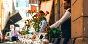 A chef sets a table on a restaurant patio preparing for summer patio service at the start of outdoor season.