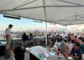 A chef carefully arranges light seasonal dishes on a rooftop dining terrace during a warm summer service