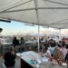 A chef carefully arranges light seasonal dishes on a rooftop dining terrace during a warm summer service