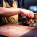 chef-assembling-grain-bowl-unsplash - GUSTOwebzine A chef carefully assembles a balanced grain bowl with layered grains, vegetables, and fresh herbs on a wooden counter