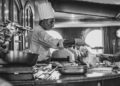 A professional chef stirs a deep pot of Neapolitan ragù over a low flame in a traditional kitchen
