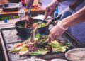 A chef carefully monitoring grill vegetables over high heat to achieve a smoky, charred finish
