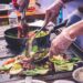 Ein Küchenchef überwacht sorgfältig Grillgemüse über großer Hitze, um ein rauchiges, verkohltes Finish zu erreichen