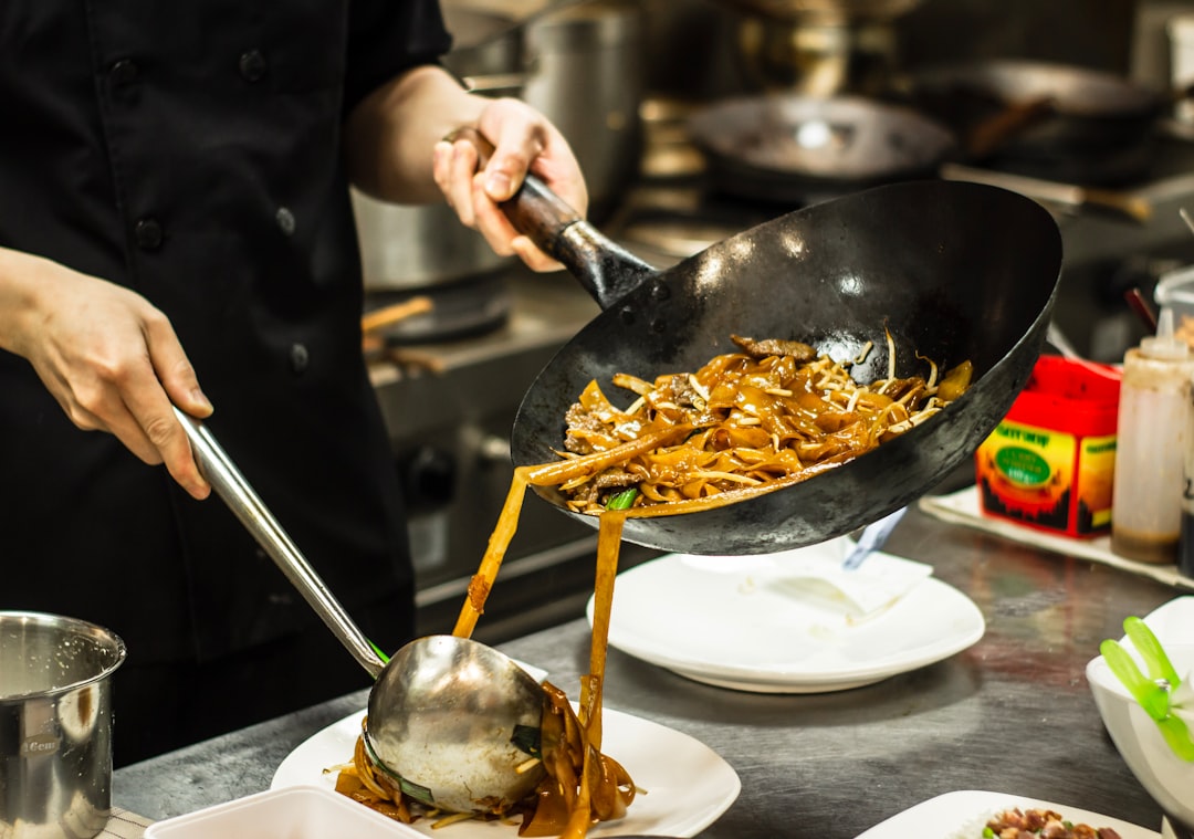A chef presenting a finished cold noodle bowl garnished with herbs and sesame seeds ready to serve