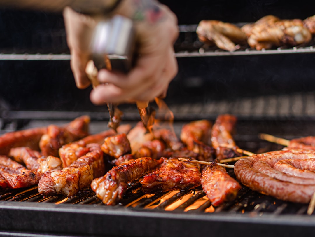 A chef rubbing bold West African spice blends onto skewered meat before placing them over an open flame grill