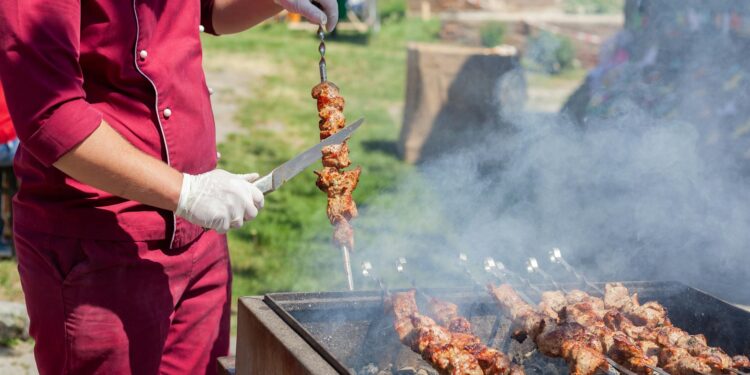 chef-setting-up-outdoor-catering-station-pexels - GUSTOwebzine Ein Profichef arrangiert Servierschüsseln an einer Outdoor-Catering-Station während eines großen Veranstaltungsortereignisses.