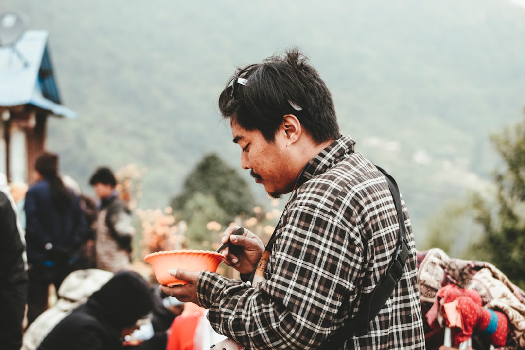 A man tasting fermented drinks at an artisan market stall, with clay vessels and grain-based probiotic beverages on display.