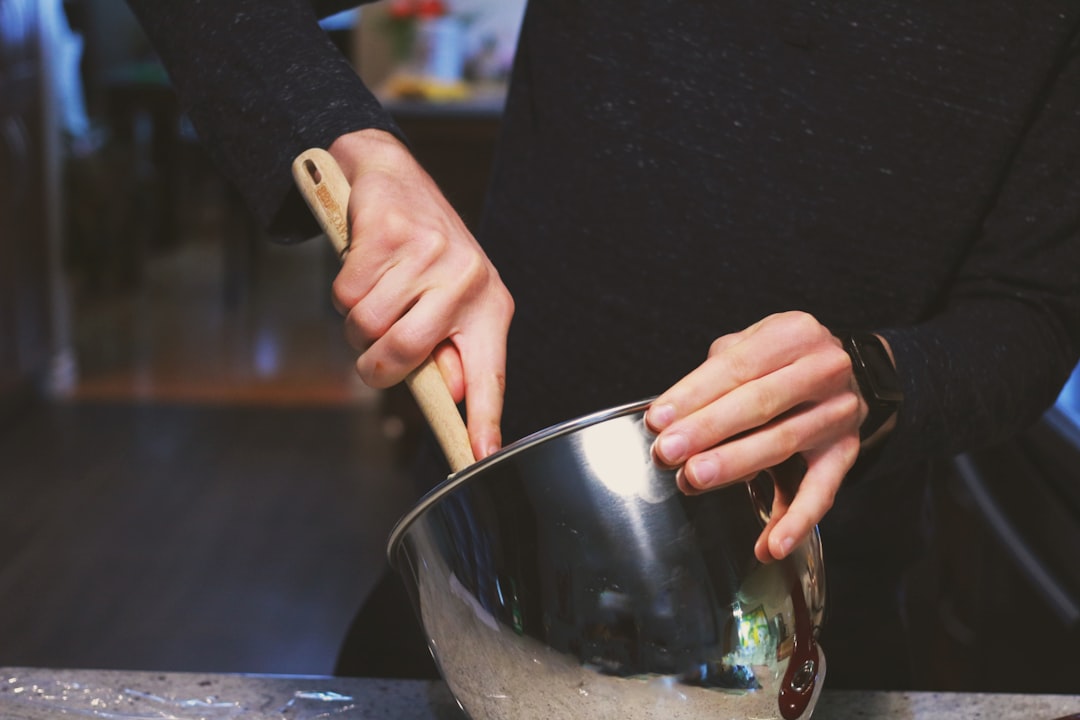 A person stirs miso caramel into a dessert bowl, demonstrating how miso creates bold sweet flavor combinations in  cooking.
