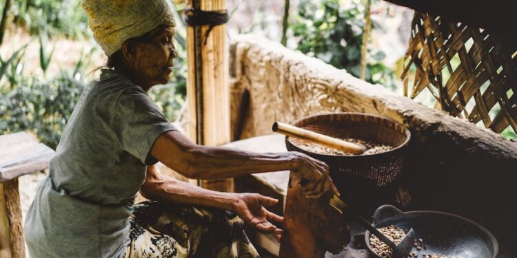 A woman carefully grinding aromatic spice blends from Africa using a traditional stone mortar and pestle in a home kitchen