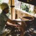 A woman carefully grinding aromatic spice blends from Africa using a traditional stone mortar and pestle in a home kitchen