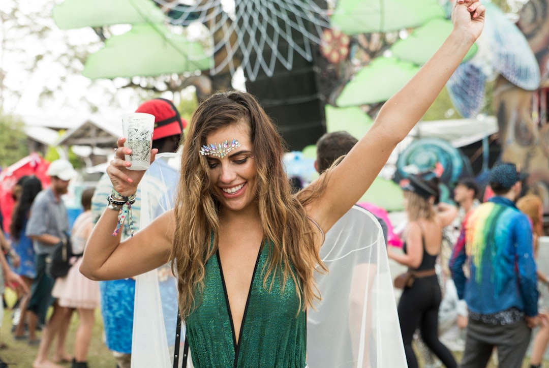 A smiling woman lifts a vibrant wine slushie at the Famous Food Festival, celebrating the diversity of global drinks .