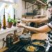 A woman carefully assembling a cold noodle bowl with fresh vegetables and sesame dressing on a bright kitchen counter