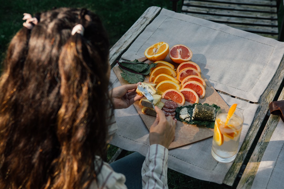 A woman unwraps individual almond from parchment paper at a picnic table, the final touch in a set of elegant picnic recipes.