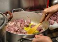 chef-braising-meat-unsplash - GUSTOwebzine Un chef cuidadosamente preparando braises lentos en una cocotte pesada, demostrando técnica clásica a fuego bajo
