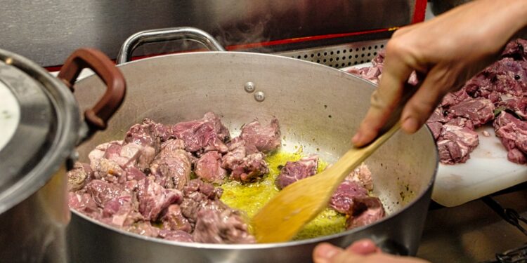 chef-braising-meat-unsplash - GUSTOwebzine Un chef cuidadosamente preparando braises lentos en una cocotte pesada, demostrando técnica clásica a fuego bajo