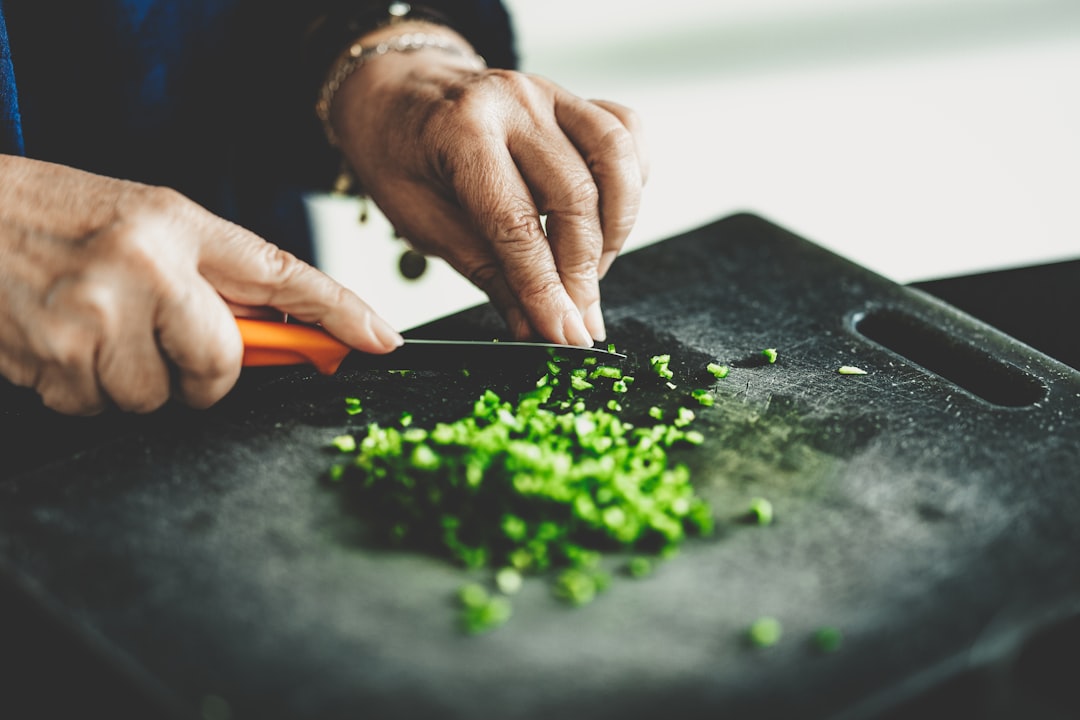 A chef finely chopping herbs and arranging warm spices on a wooden board to prepare an authentic Moroccan chermoula marinade.