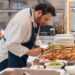 chef-plating-breakfast-unsplash - GUSTOwebzine Un chef de hotel prepara cuidadosamente un plato de desayuno de hotel de origen local que presenta verduras estacionales y granos regionales
