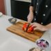chef-slicing-tomatoes-kitchen-unsplash - GUSTOwebzine Ein Chef, der seine Messerkünste demonstriert, während er frische Sommertomate auf einem Holzschneidebrett schneidet