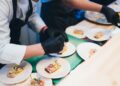 A food buyer tasting specialty food samples at a busy trade show booth in New York City